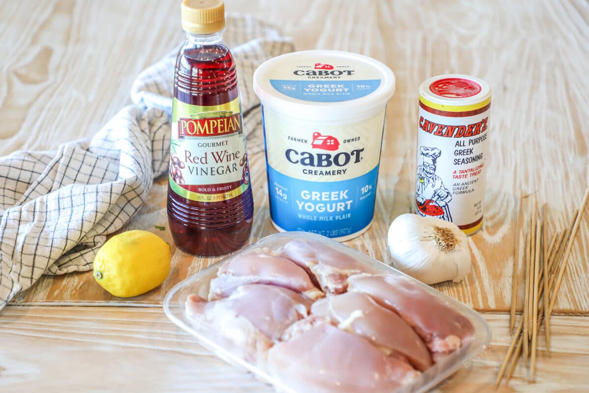 Ingredients needed to make chicken gyro skewers. On wooden background.
