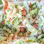 a scoop of creamy pasta salad being taken out of a large bowl.
