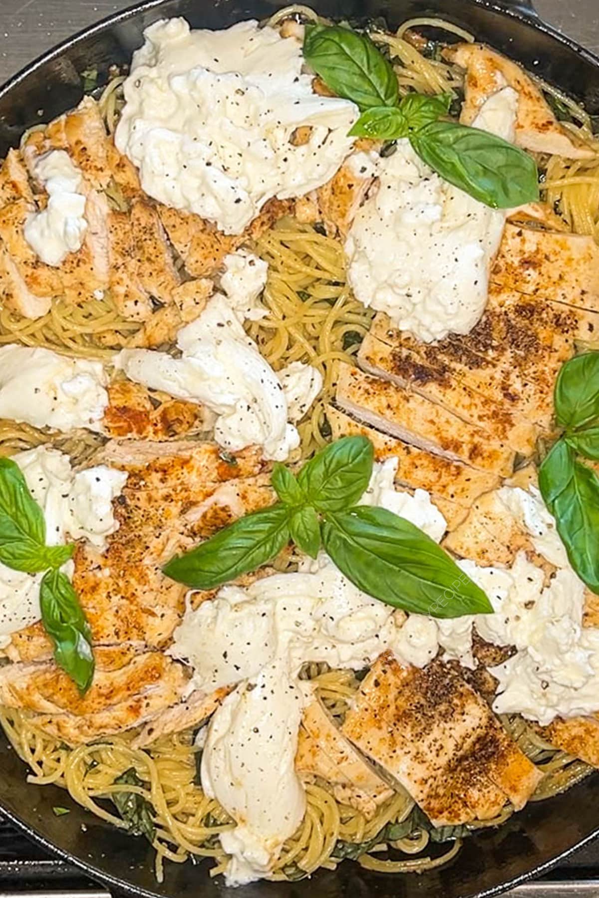 Brown butter spaghetti with chicken, basil and burrata in pan