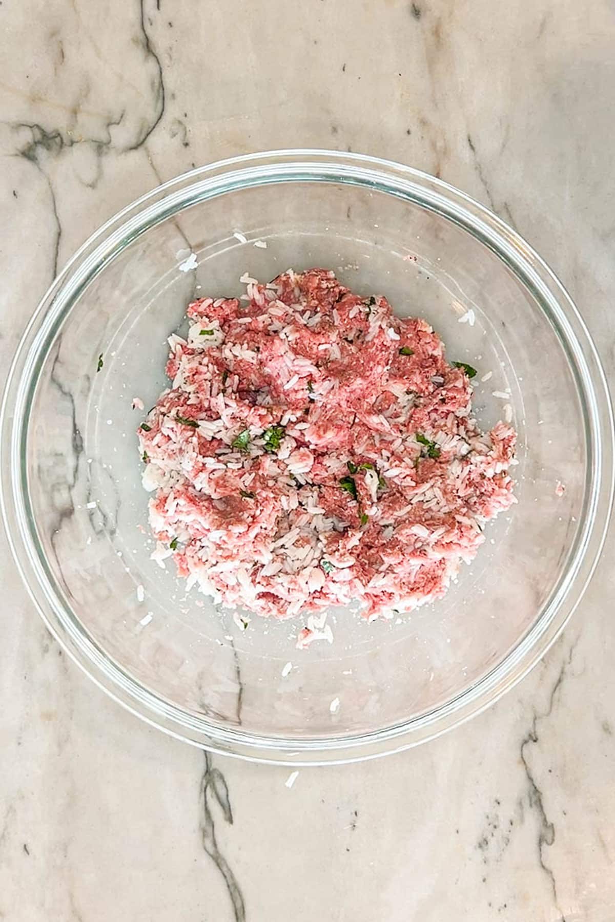 Glass bowl with stuffing mixture for stuffed peppers. Bowl on a marble background.