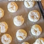Lemon cake mix crinkle cookies on baking sheet with parchment paper. On a wooden background