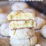 Lemon cake mix crinkle cookies stacked. Two half cookies on top. Cookies in background. On a sheet pan with parchment paper