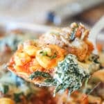 Close up of a portion of cheesy sausage tortellini on a metal spatula.