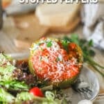 White plate with a slow cooker stuffed pepper and side salad. Wooden background with wooden board and parmesan cheese block, fresh parsley and onion.