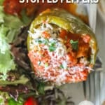 White plate with a slow cooker stuffed pepper and side salad. Fork on plate