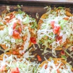above image of baked tostadas piled with lettuce and tomato.