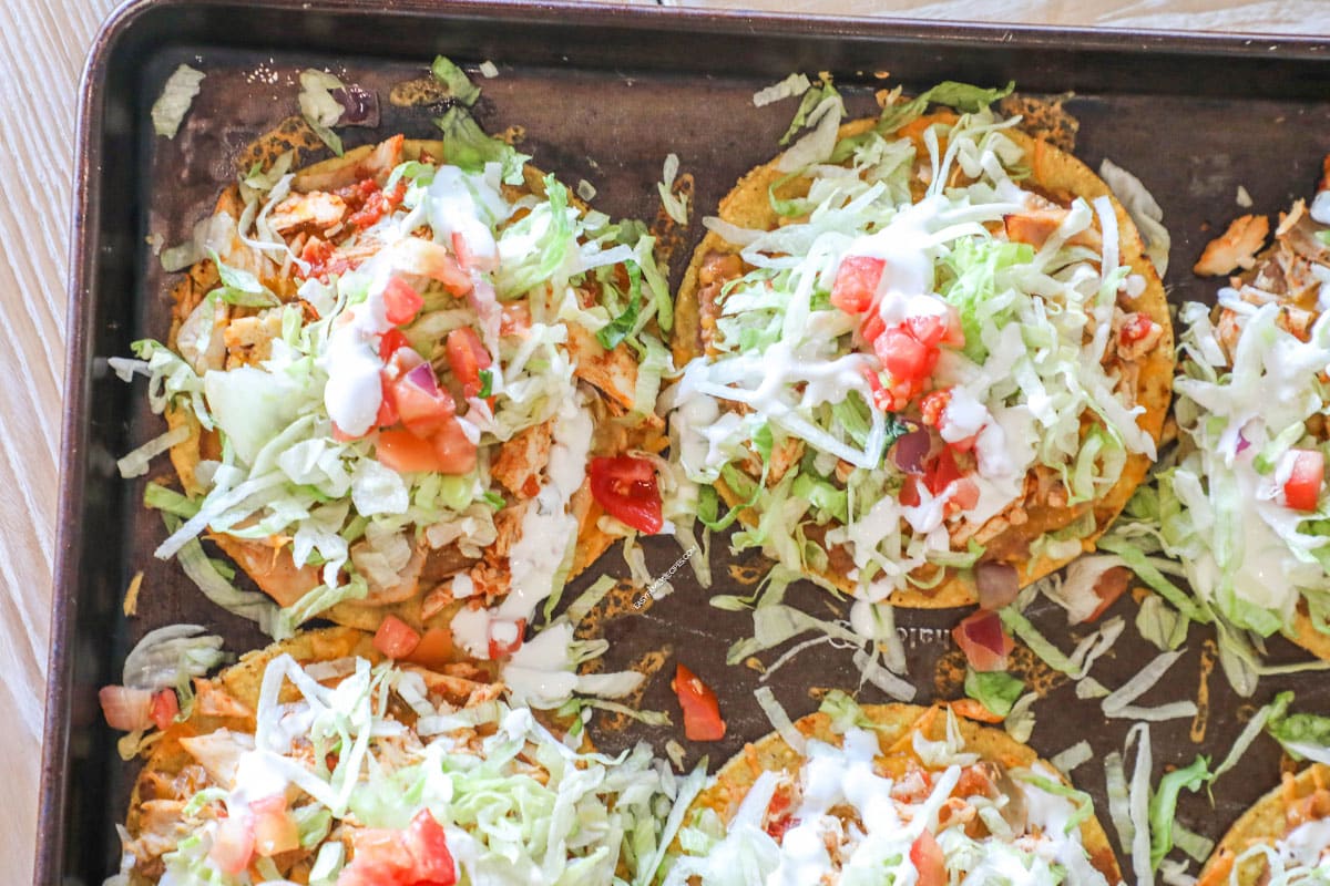 above image of baked tostadas piled with lettuce and tomato.