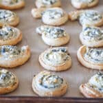 Spinach feta puff pastry swirls on parchment paper lined baking sheet.