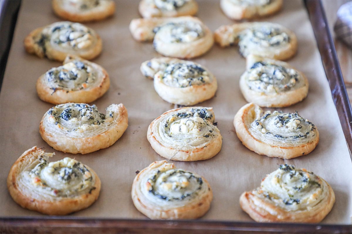 Spinach feta puff pastry swirls on parchment paper lined baking sheet.