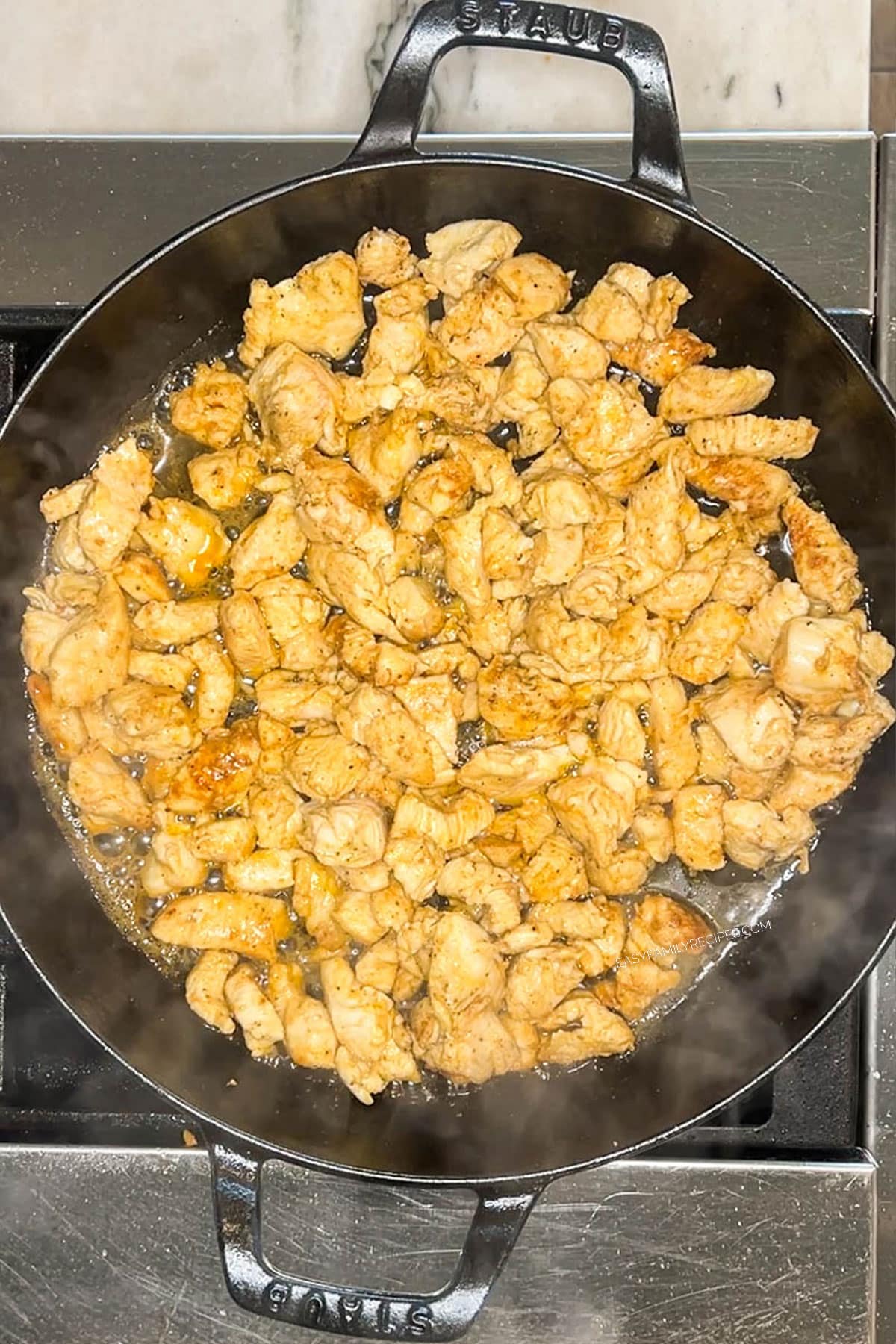 Chicken pieces cooking in pan on stove