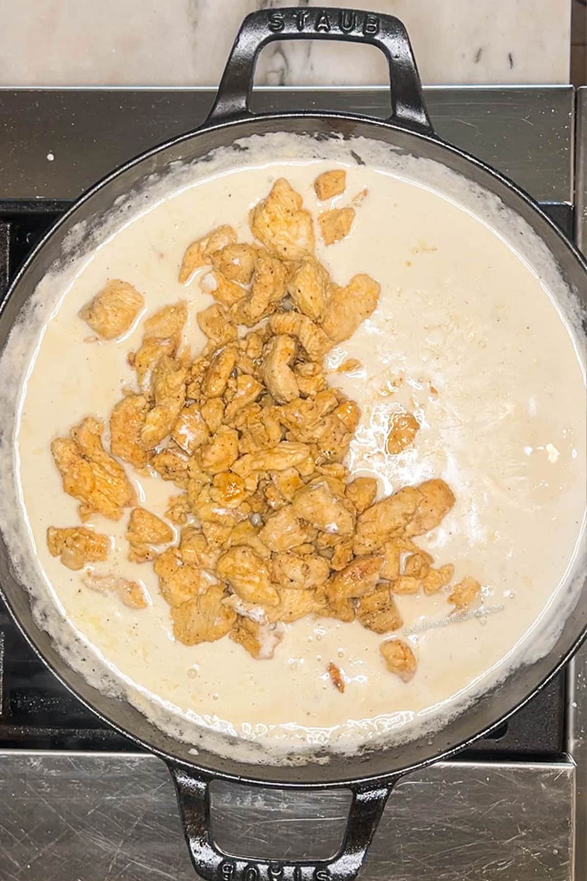 Bite size chicken added to creamy sauce