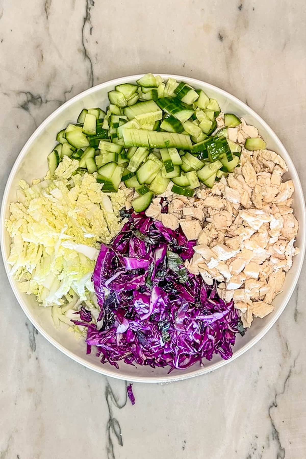White bowl with chicken, cabbage and cucumber