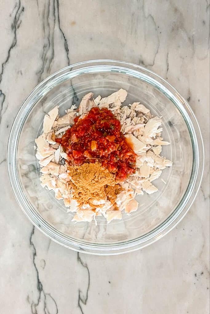 mixing bowl filled with chicken, salsa, and taco seasonings.