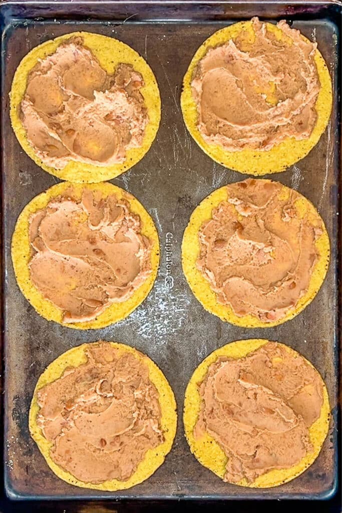 six tostada shells topped with refried beans.