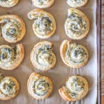 Spinach feta puff pastry swirls on parchment paper lined baking sheet.