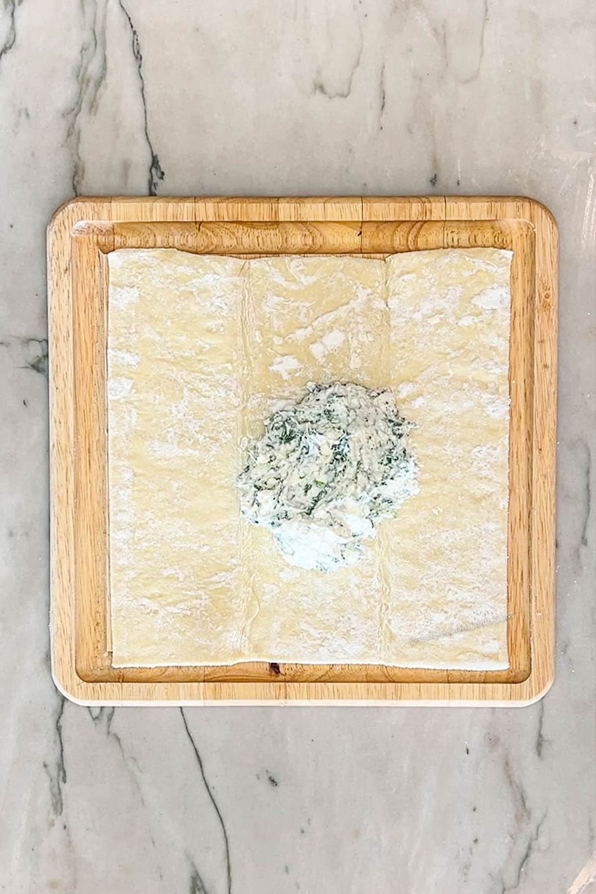 Mixture on puff pastry. On a wooden board.