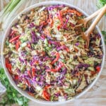 Thai Style Chicken Salad with Peanut Dressing in a large white bowl with wooden spoons. On a wooden backdrop