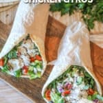 Two baked chicken gyros on a wooden board.