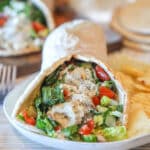 Baked chicken gryo served on a plate with chips.