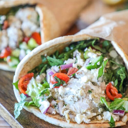 Close up view of a baked chicken gyro on a wooden board.