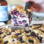 berry breakfast cake being lifted out of a baking dish.