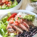 Pico de gallo on top of sliced carne asada in a bowl of rice.