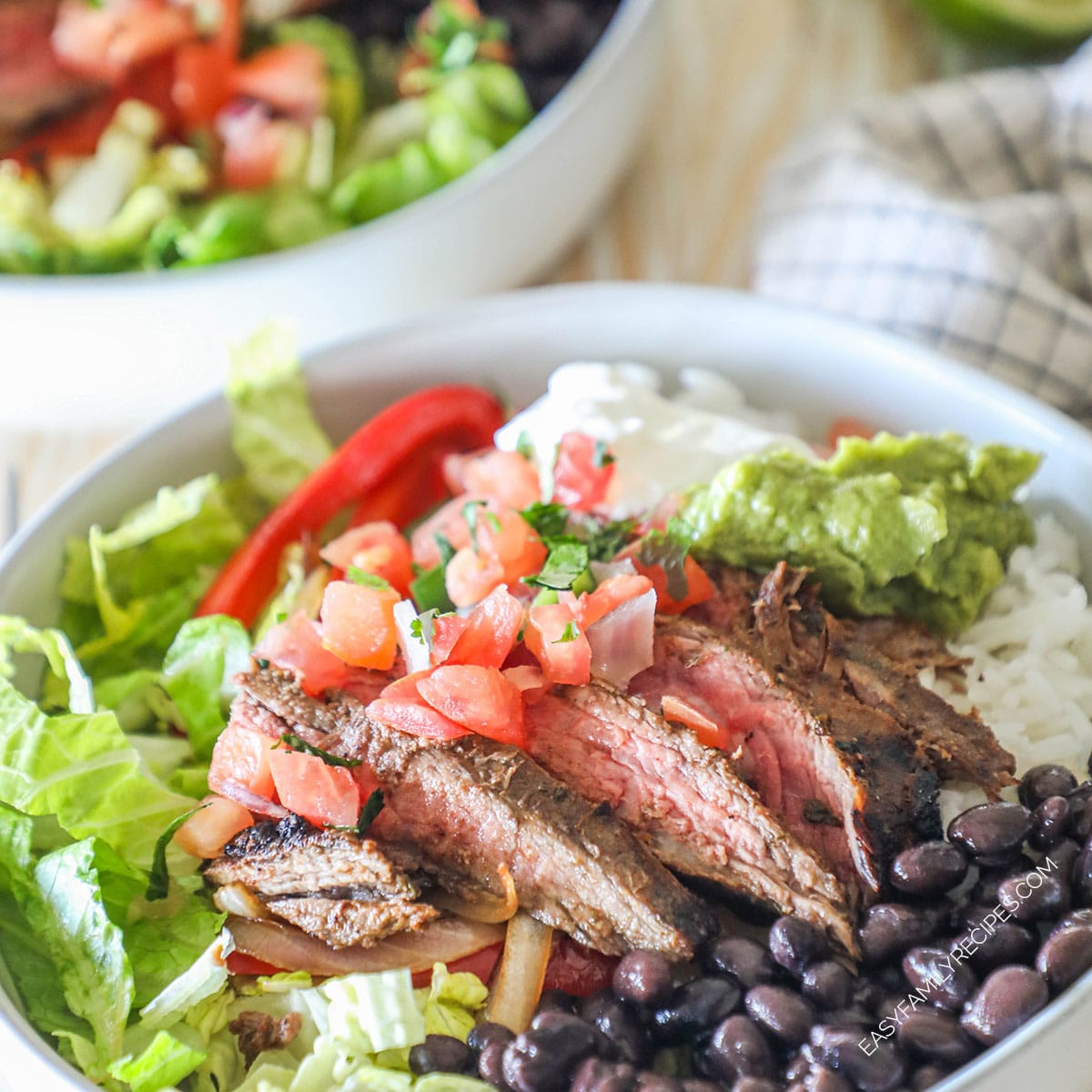 Pico de gallo on top of sliced carne asada in a bowl of rice.