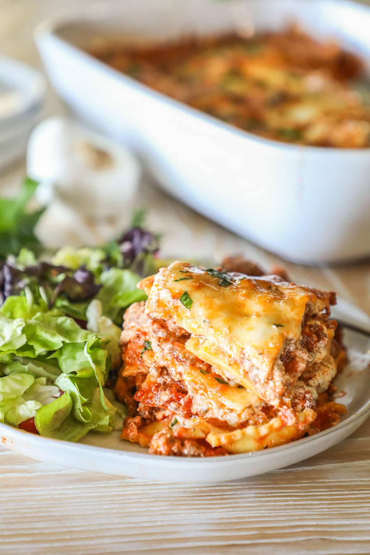 Slice of million dollar ravioli bake on a plate with salad.