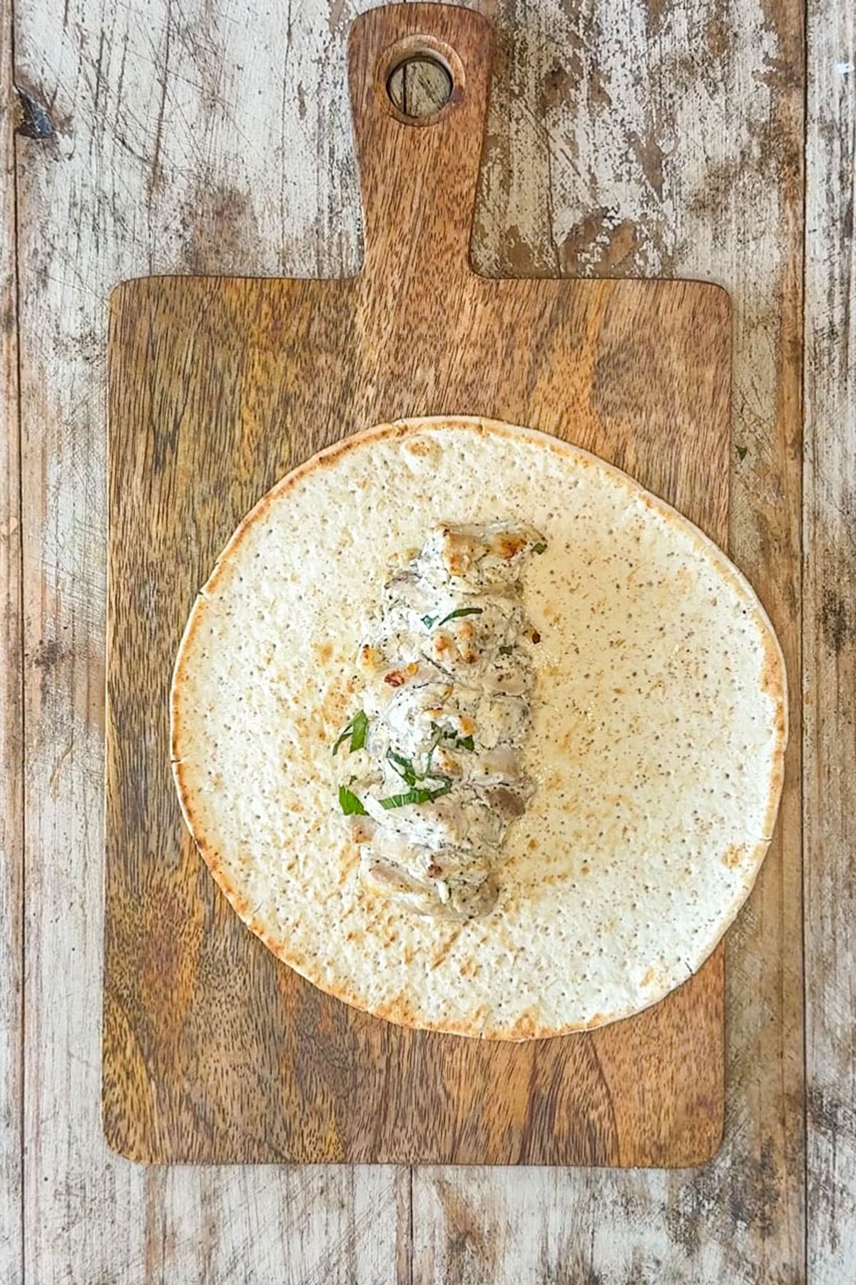 Baked chicken gryo meat placed on top of a pita round.