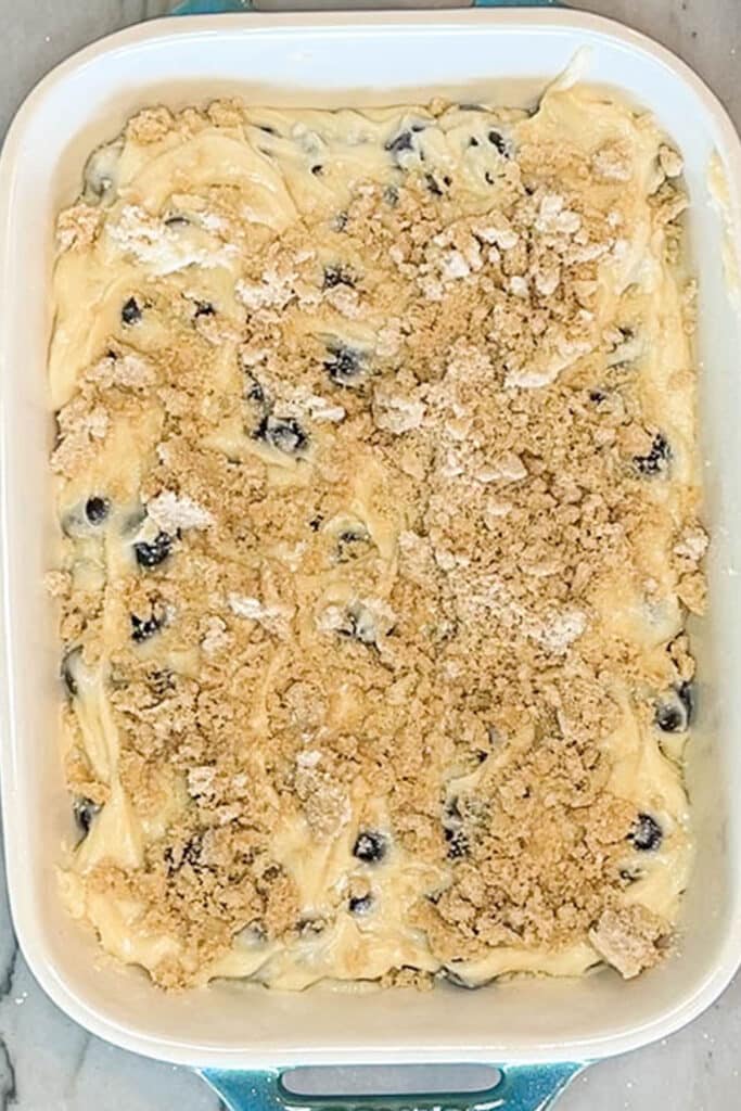 above image of breakfast cake batter topped with streusel in a baking dish.