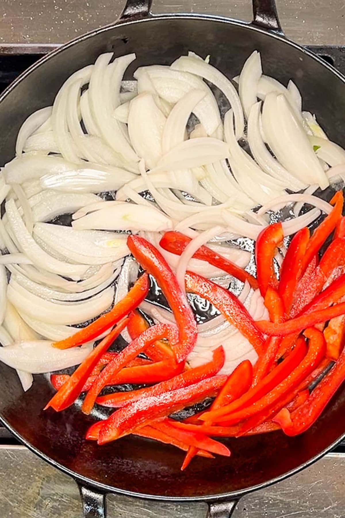 Sauteing onions and red peppers in a skillet.