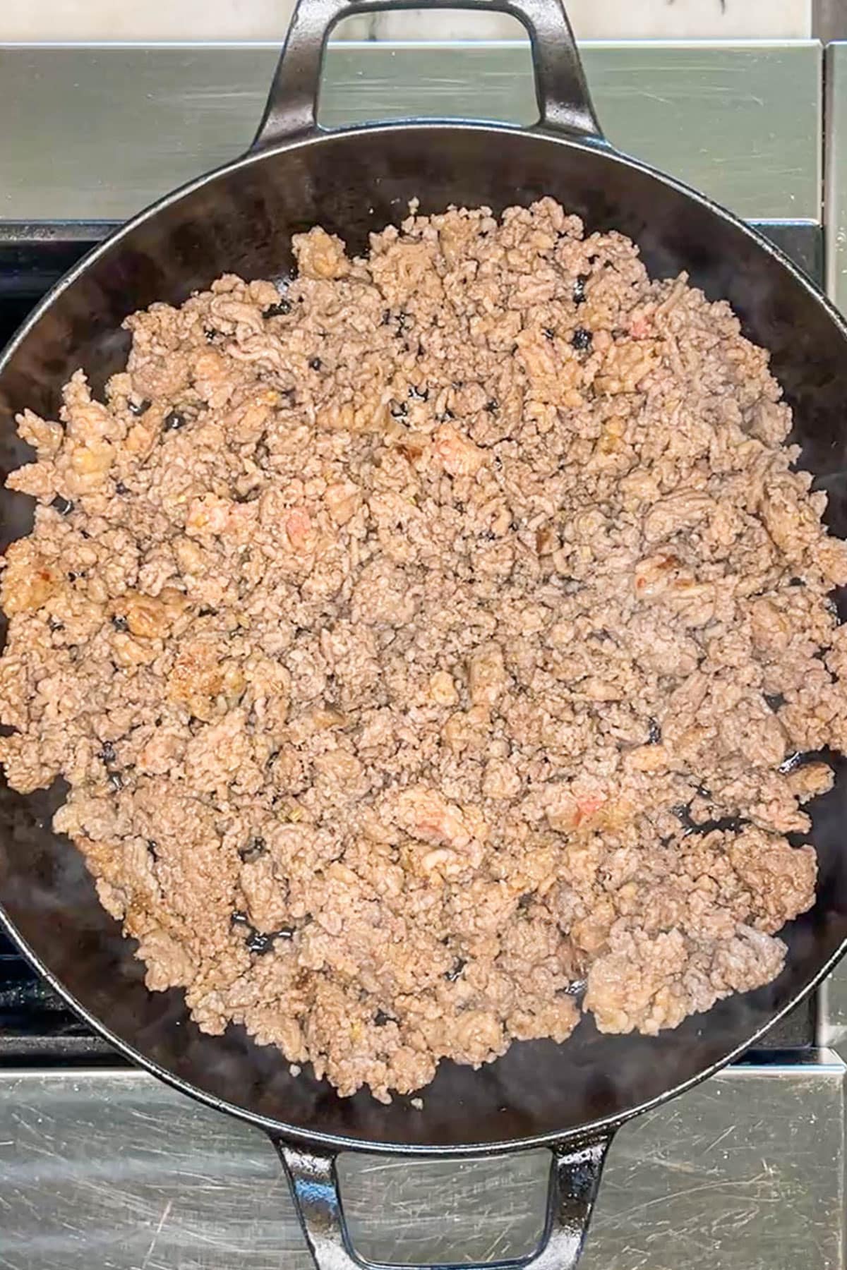 Ground meat being browned in a skillet.