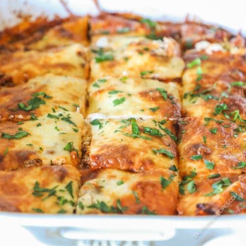 Close up of baked million dollar ravioli sliced into squares and garnished with parsley.