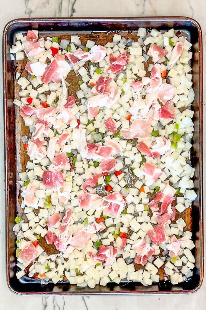 potatoes o'brien and bacon layered on a baking sheet.