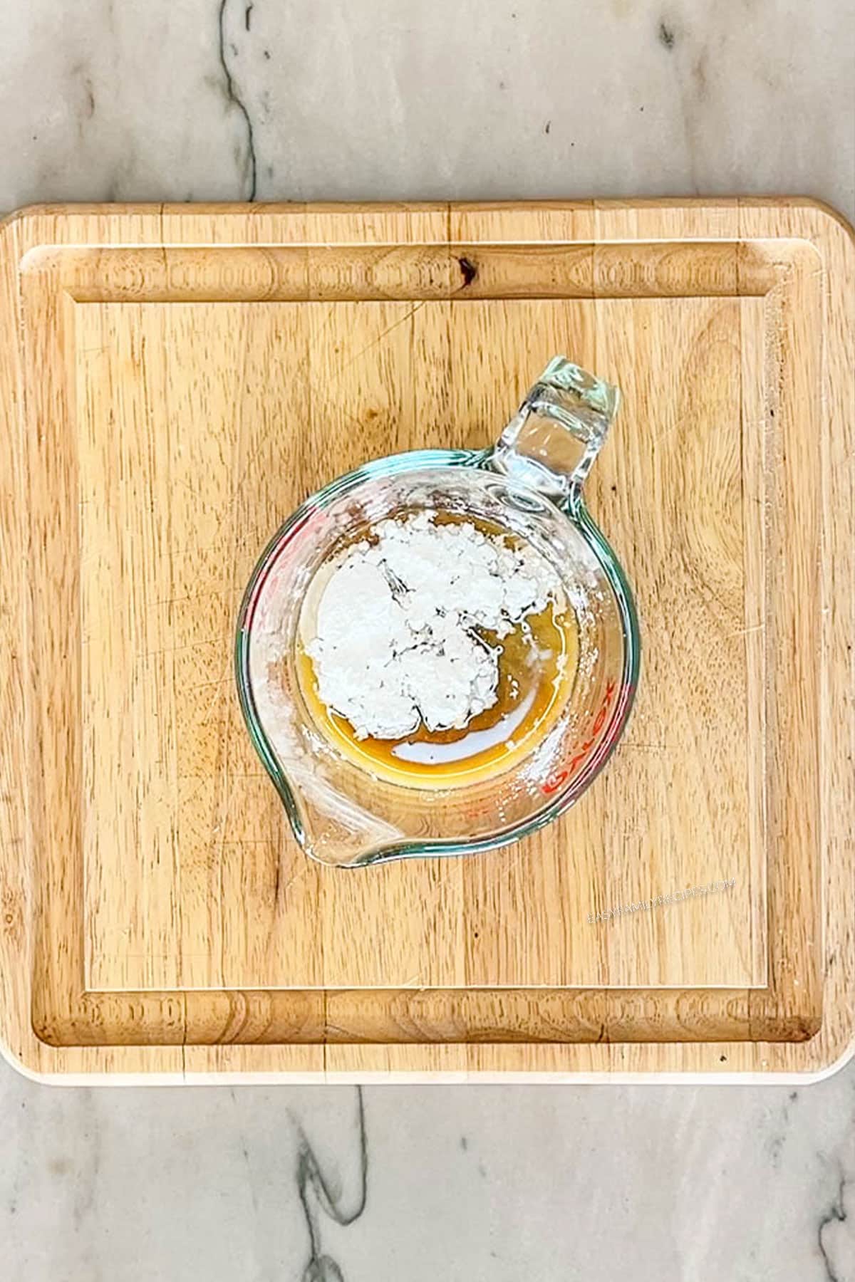 Step one of making sheet pan orange chicken. Bowl of ingredients for sauce. On a wooden board
