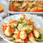Individual serving of sheet pan orange chicken with white rice. On a white plate. Sheet pan in background.