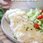 a piece of baked chicken breast with cheese served on a plate with a side salad.