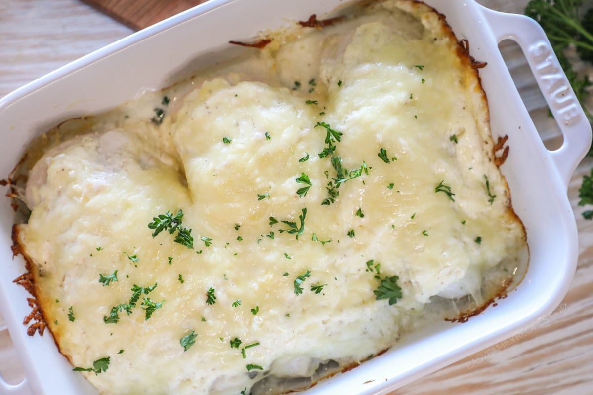 above image of a baking dish with three slices of chicken topped with cream cheese sauce and cheese.
