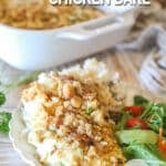 Individual serving of french onion chicken bake on white dish with side salad- on a wooden background with full pan in background