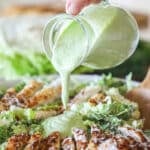 homemade dressing being drizzled over a salad.