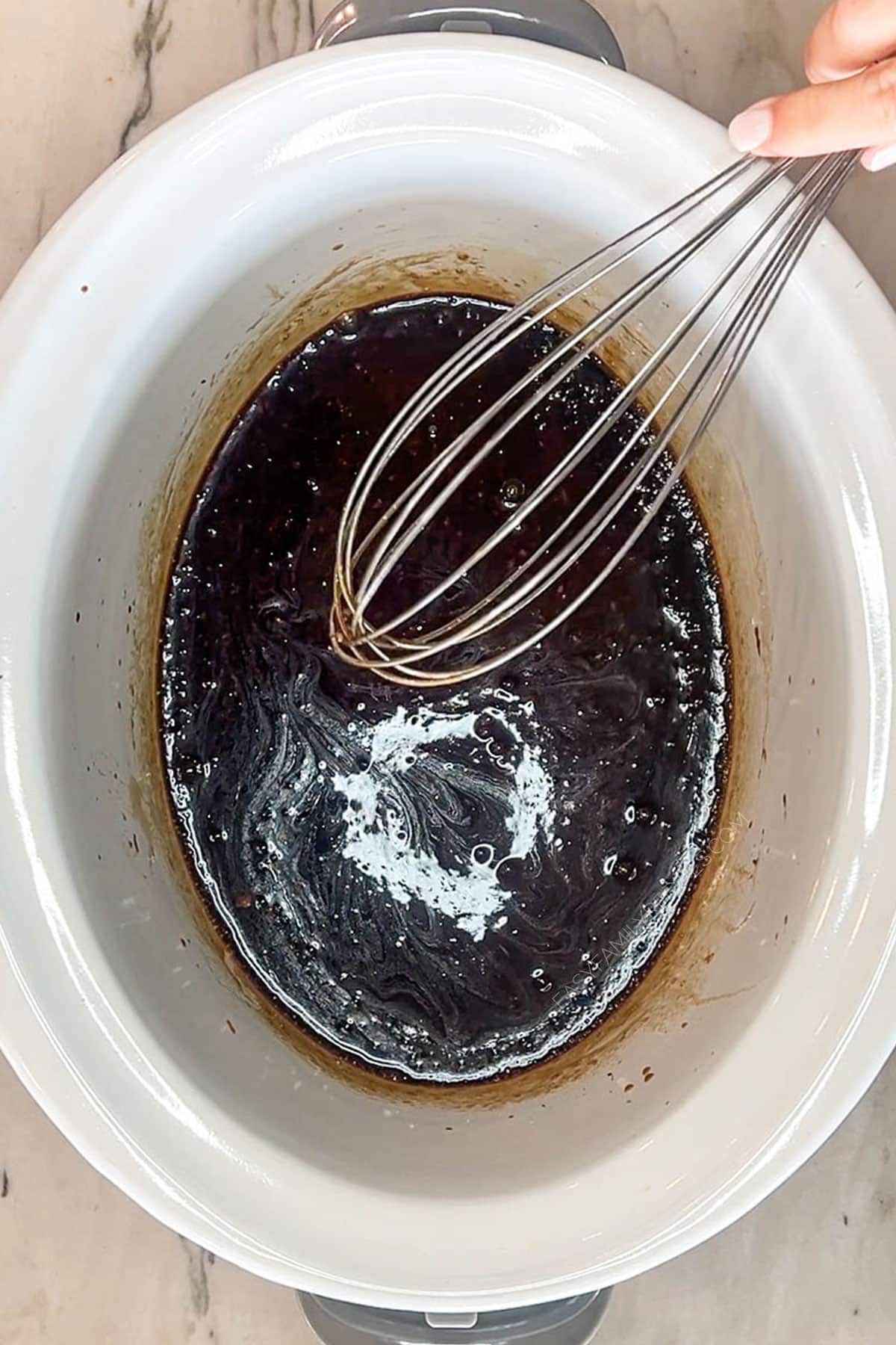 Whisking together the huli huli sauce in the bottom of a crockpot.