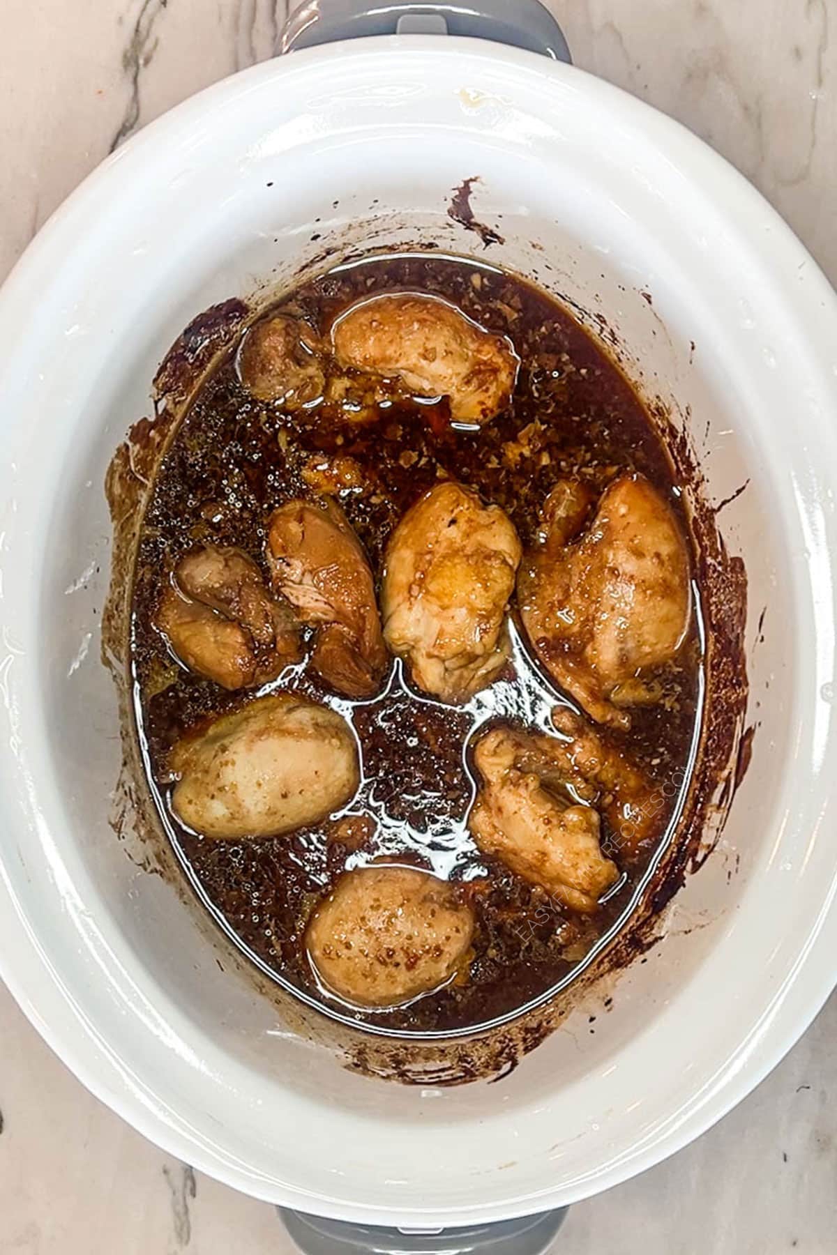 Overhead shot of huli huli chicken in sauce in a crockpot.