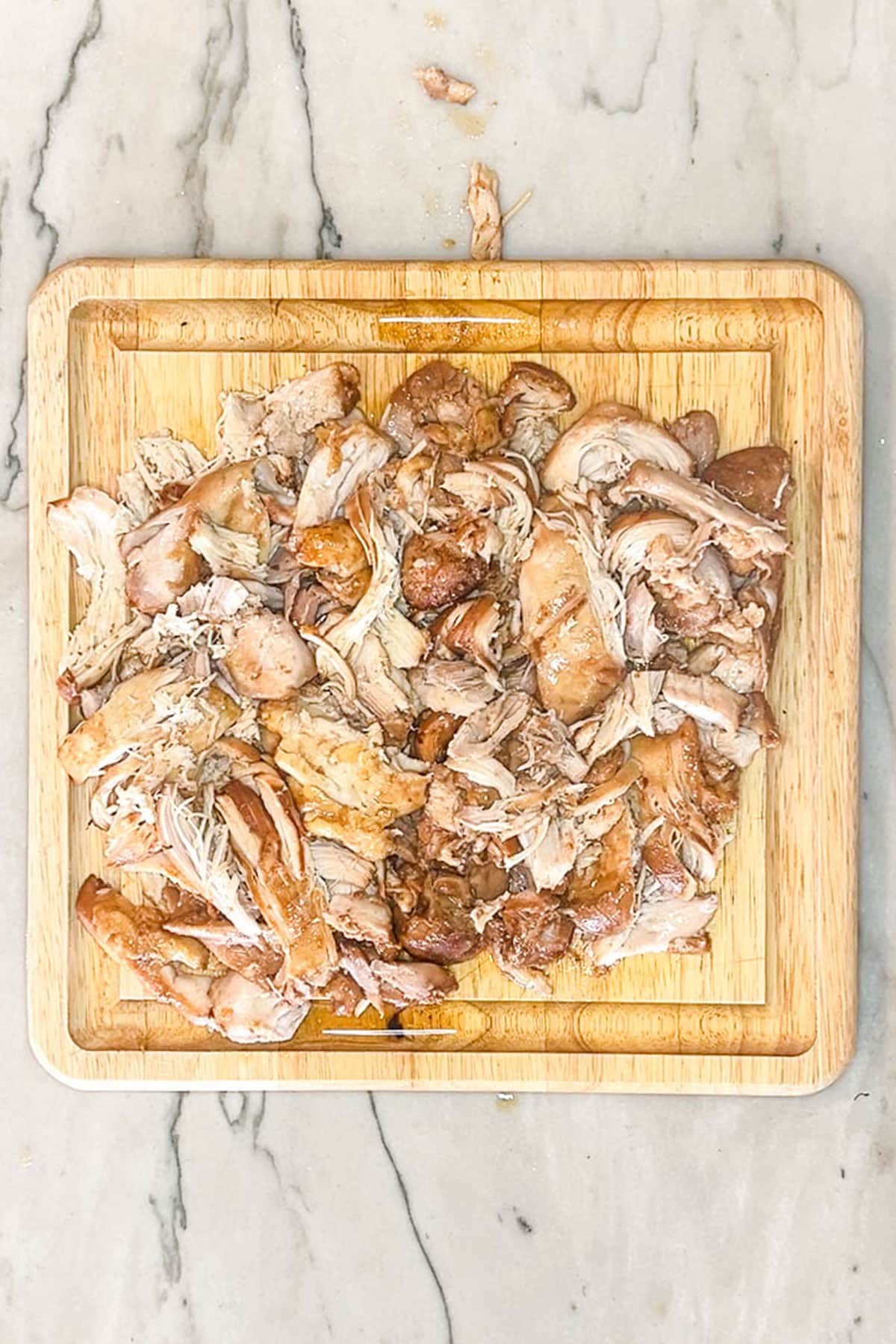Huli Huli chicken shredded up on a wooden board.