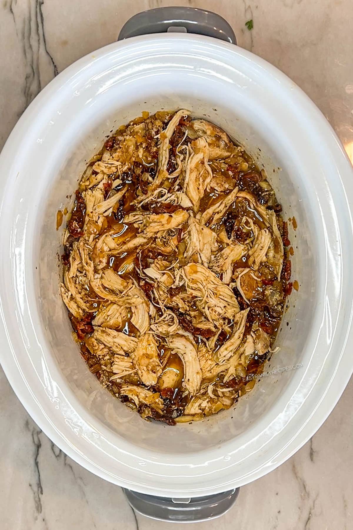 Shredded Tuscan chicken in a crockpot.