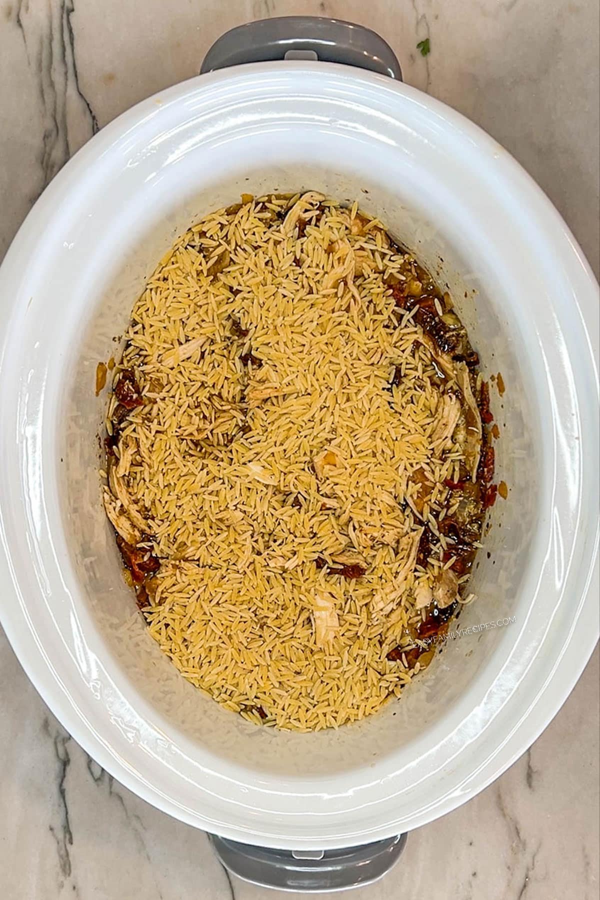 Dried orzo added to the shredded Tuscan chicken in the crockpot.