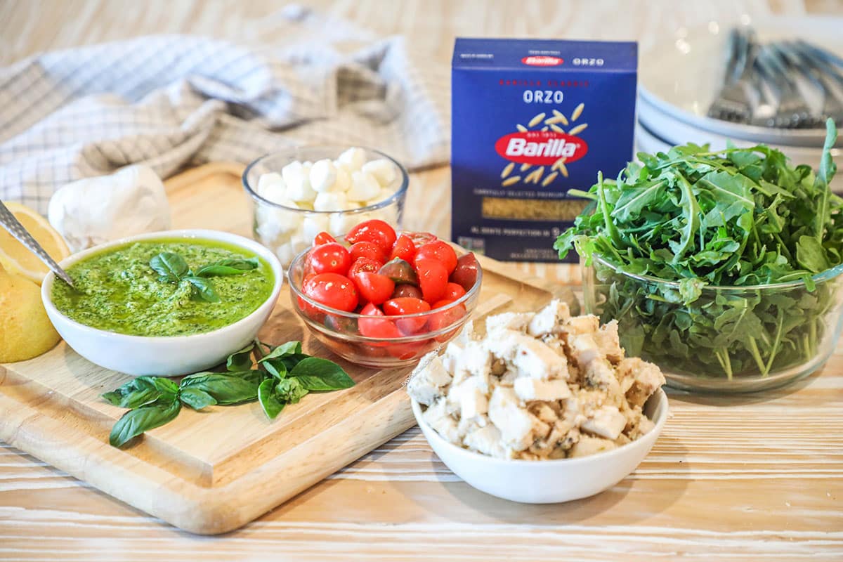 ingredients needed to make pesto chicken salad with orzo- on a wooden background