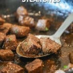balsamic steak bites seared and cooked in cast iron skillet with metal spoon lifting them out