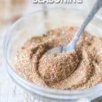 Carne Asada Seasoning Blend mix together in a clear bowl with a spoon coming out. On a wooden background