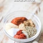 The various spices for Carne Asada Seasoning Blend in a clear bowl on a wooden background