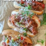Overhead shot of sausage and peppers served in rolls, garnished with parmesan and parsley.